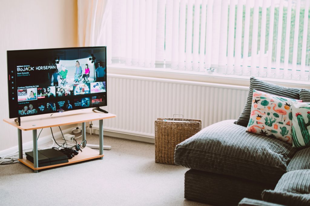 Imagem de um sofá e de uma televisão ligada em um programa animado